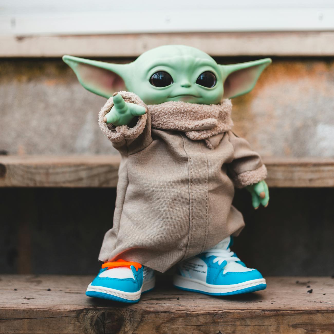 An image of Grogu, "Baby Yoda," pointing. He's wearing a brown robe and blue sneakers.
